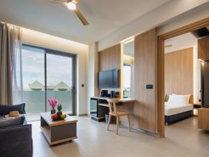 a living room with a bed and a desk with a television at Oscar Suites & Village in Agia Marina Nea Kydonias