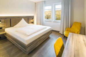 a bedroom with a bed and a chair and a table at Hotel Sonne Rudersberg in Rudersberg +13 photos
