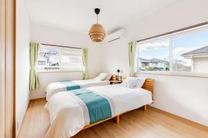 two beds in a room with a window at Itoshima Private Villa 4LDK 4-Bedroom in Itoshima