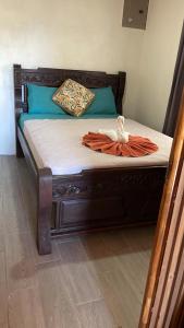 a bed with a wooden frame with an orange robe on it at Hostel La Suerte in Monteverde Costa Rica