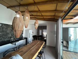 a dining room with a long wooden table and chandeliers at Casa Green Ville in Prado