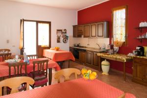 a kitchen with red walls and wooden tables and chairs at Casolare Nelle Saline in Torre Nubia