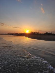 a sunset on a beach with the sun setting at POUSADAGiraGarden Containers in Arroio do Silva
