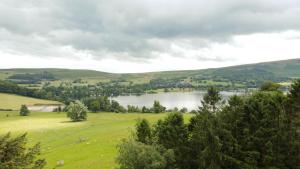 a green field with a lake in the distance at Waterfoot Park in Pooley Bridge
