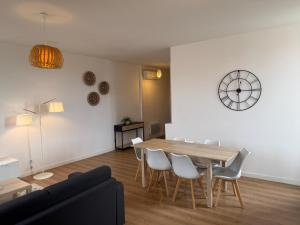 a living room with a table and chairs and a clock at ABEILLE - 2 chambres et 1 canapé-lit, 1er étage, parking in Castelsarrasin