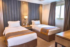 a hotel room with two beds and a desk at Myrtle Al Shohadaa Serviced Apartments in Riyadh +39 photos