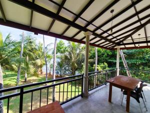 a balcony with a table and a view of trees at Lake view Oasis Koggala in Malalagamaduwa