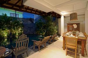 a patio with a table and chairs and a swimming pool at Juan Villa Legian in Seminyak