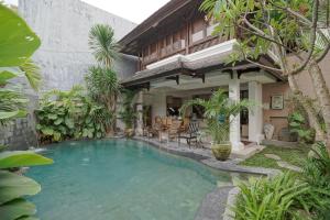 a swimming pool in front of a house at Juan Villa Legian in Seminyak