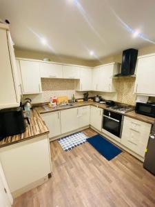 a kitchen with white cabinets and a blue rug on the floor at Stay with LL in Doncaster