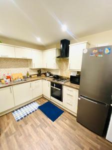 a kitchen with white cabinets and a stainless steel refrigerator at Stay with LL in Doncaster