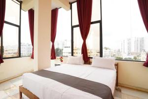 a bedroom with a large bed with large windows at Collection O Delta Electronics Metro Station Bangalore Formerly New Kick in Kammasandra