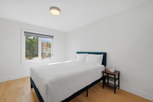 a white bedroom with a bed and a window at Quiet and Convenient Retreat in Hammonds Plains