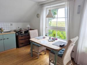 a kitchen with a table and chairs and a window at Landhaus am Deich in Dornum
