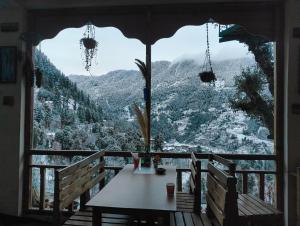 a table on a balcony with a view of a mountain at MOZO Inn&Cafe Jibhi in Banjār
