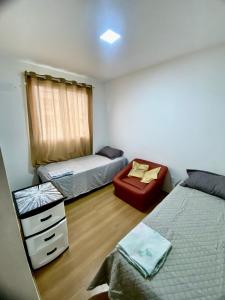a small bedroom with two beds and a chair at Ilha Aruba Condomínio na Cohama próx a praia in São Luís