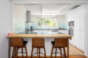a kitchen with a counter and two stools in front of it at Spacious Multifunctional 5BR Retreat with Backyard in Bayswater