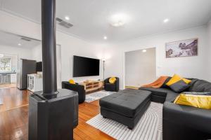 a living room with a black couch and a fireplace at Spacious Multifunctional 5BR Retreat with Backyard in Bayswater