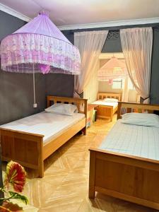 a bedroom with two beds and a purple umbrella at Esther Villas Home in Boma la Ngombe