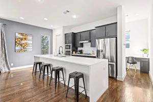 a kitchen with a large white counter and stools at King-Sized Comfort with Rooftop Skyline Views in Dallas