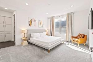 a white bedroom with a bed and a chair at King-Sized Comfort with Rooftop Skyline Views in Dallas