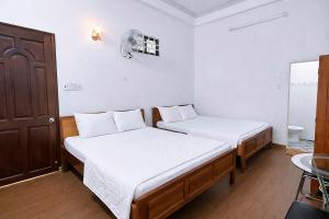 a bedroom with two beds and a door and a table at Nhà Nghỉ Long Nhi in Nhơn Trạch