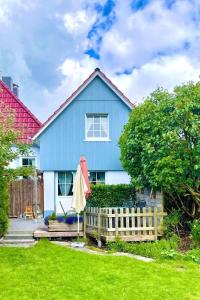 a blue house with a fence and an umbrella at Friesenhus in Butjadingen