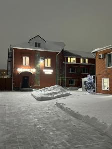 a snow covered driveway in front of a brick building at Welcome Hotel in Kostanay