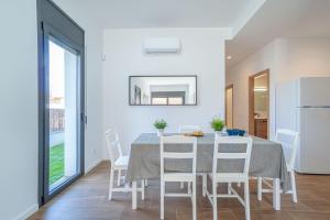 a dining room with a table and white chairs at Jouvacations Villa Osona in Vilafant