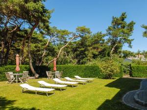 a row of chairs and tables with umbrellas on a lawn at Burg Roland Wohnung 06 in Dierhagen