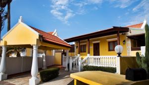 a yellow house with a white fence and a table at Cunucu Villa with Private Jacuzzi in Soledad