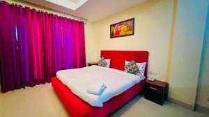 a bedroom with a red bed with purple curtains at The Hotel Am Bliss in Gurgaon