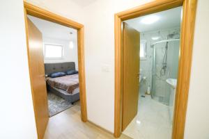 a bathroom with a bed and a shower and a mirror at Apartman Šarabaća in Bajagić
