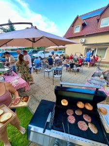 a grill with donuts on it with people sitting under an umbrella at Harmónia Panzió in Bogács