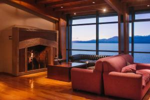 a living room with a fireplace with a view of the water at Alma Del Lago Suites & Spa in San Carlos de Bariloche