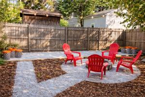four red chairs and a table in a backyard at Remodeled Modern Home - private backyard & games! in Louisville