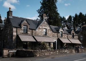 an old stone building with black roofs on a street at The Grandtully Hotel in Grandtully