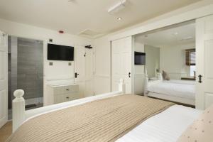a white bedroom with a bed and a bathroom at The Cricket Inn in Kingsbridge