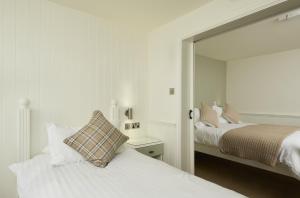 a white bedroom with two beds and a mirror at The Cricket Inn in Kingsbridge