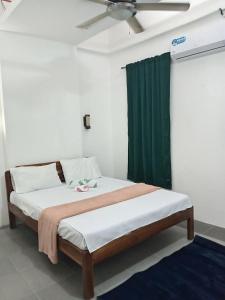 a bed in a room with a green curtain at La Bottega Pension House in Roxas