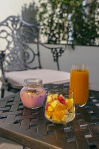 a table with a bowl of fruit and two glasses of juice at Hotel Passport Tbilisi in Tbilisi City