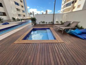 a swimming pool on a wooden deck with chairs on a building at Santorini Piscina Hidro Academia Salt Hospital Premium Jaime Câmara Mercatto Store Moreira Marista Blue Fit Perdomo Vaca Brava Goiânia Shopping Areião Marista Ze Abílio Serrinha Campo do Goiás Hailé Pinheiro in Goiânia +25 photos