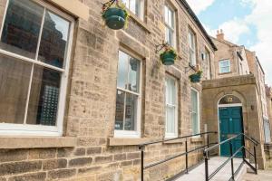 ein Backsteingebäude mit grüner Tür und Fenstern in der Unterkunft 32 Bondgate Without in Alnwick