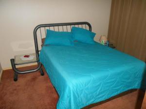 a bed with a blue comforter in a bedroom at Pilot Inn Accommodation in Kempton Park