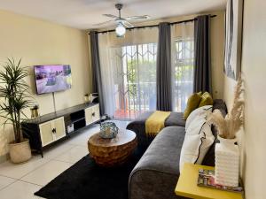 a living room with a couch and a tv at KADESE Holiday North Beach Durban in Durban