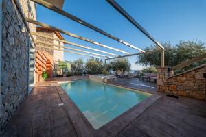 a swimming pool in a house with a stone wall at Dio Escapes Villas in Poulithra