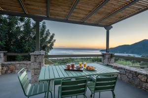 a green table and chairs on a patio with a view at Dio Escapes Villas in Poulithra