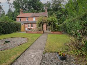 a garden with a brick house and a walkway at 2 Aqueduct Cottages in Wrexham