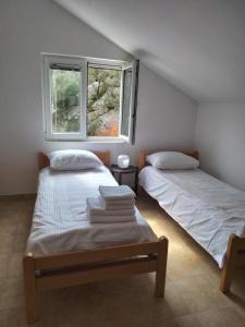 two beds in a room with two windows at Hillside Haven in Sutorina