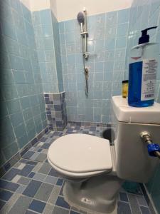a bathroom with a toilet with a blue tiled wall at Beni'o Suite in Adiapo-Doumé